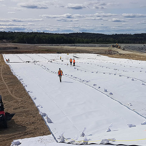 Men on a geomembrane doing leak location at the Laronde mine
